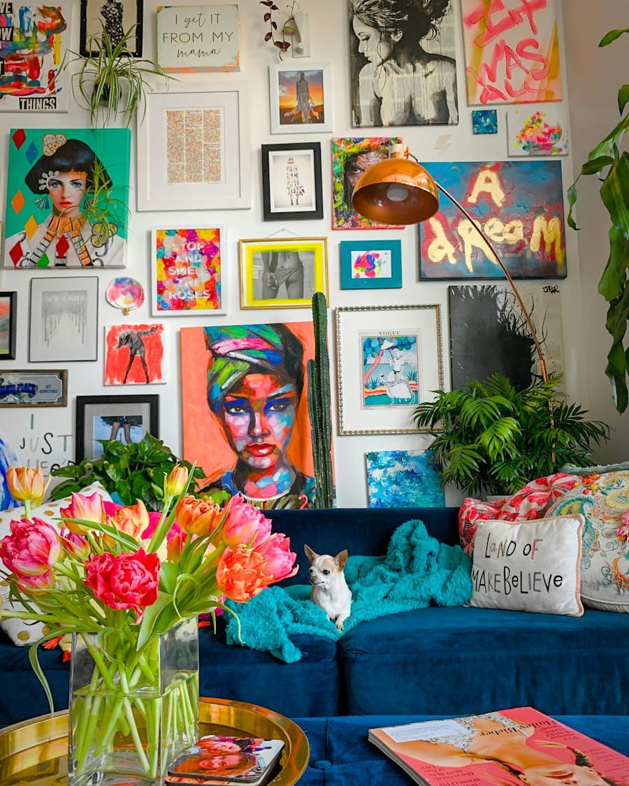 A colorful living room with a blue sofa and a wall of framed pictures